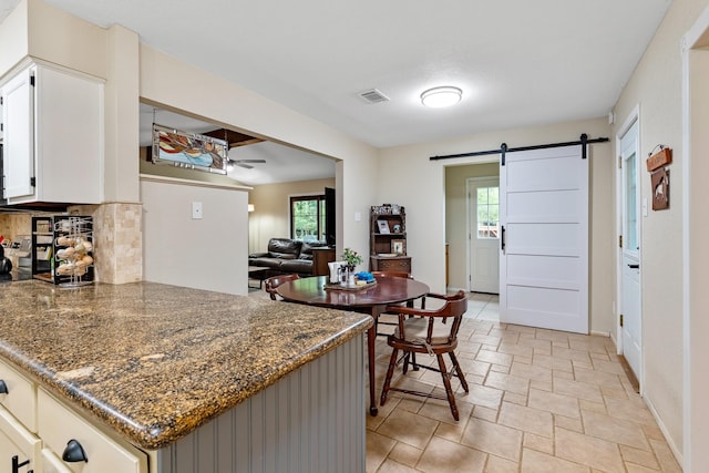 4205 Wade Rd, Brookshire, TX 77423 - kitchen featuring a barn door, stone tile floors, healthy amount of natural light, and backsplash