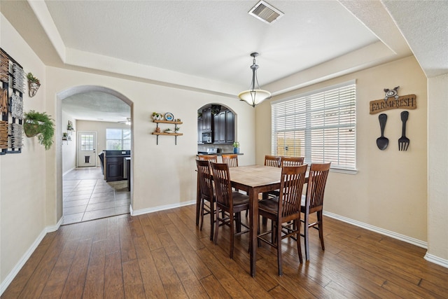 8234 Nagy Hill St, Spring, TX 77379 - dining area featuring arched walkways, a tray ceiling, and dark wood-style flooring