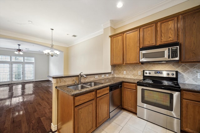 9007 Harbor Hills Dr, Houston, TX 77054 - kitchen with stainless steel appliances, a peninsula, brown cabinets, dark stone countertops, and tasteful backsplash