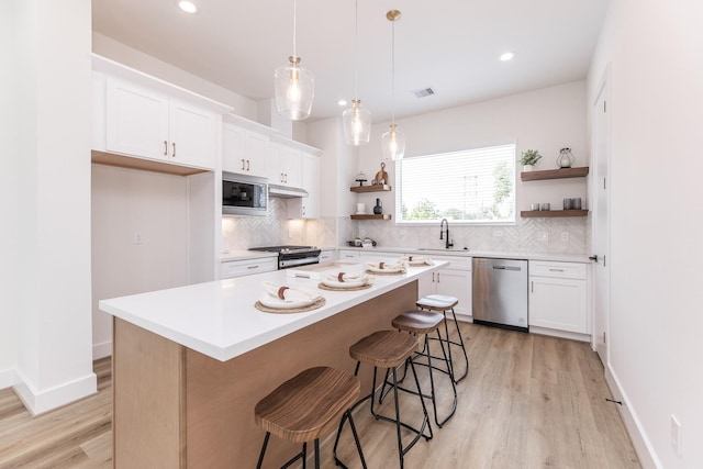 1615 Erin St, Houston, TX 77009 - kitchen featuring appliances with stainless steel finishes, open shelves, light wood-type flooring, decorative backsplash, and recessed lighting