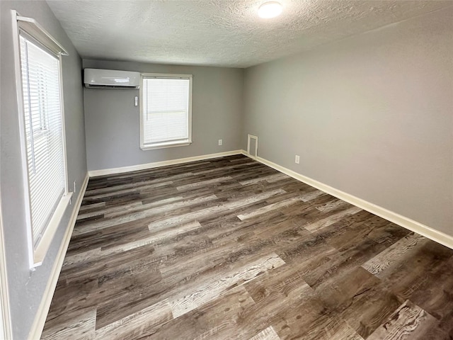 323 Texas St, Freeport, TX 77541 - unfurnished bedroom with a wall mounted AC, a textured ceiling, and dark wood finished floors