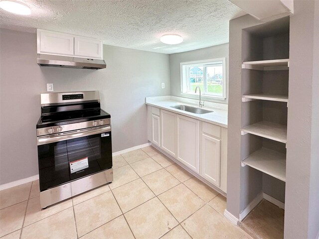 323 Texas St, Freeport, TX 77541 - kitchen with stainless steel electric stove, under cabinet range hood, light countertops, white cabinets, and light tile patterned floors