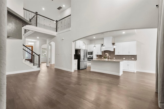 6126 Garden Lakes Ln, Sugar Land, TX 77479 - unfurnished living room with arched walkways, stairs, dark wood-style flooring, a high ceiling, and recessed lighting