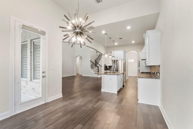 6126 Garden Lakes Ln, Sugar Land, TX 77479 - kitchen with arched walkways, a chandelier, white cabinetry, dark wood-type flooring, and a kitchen island with sink
