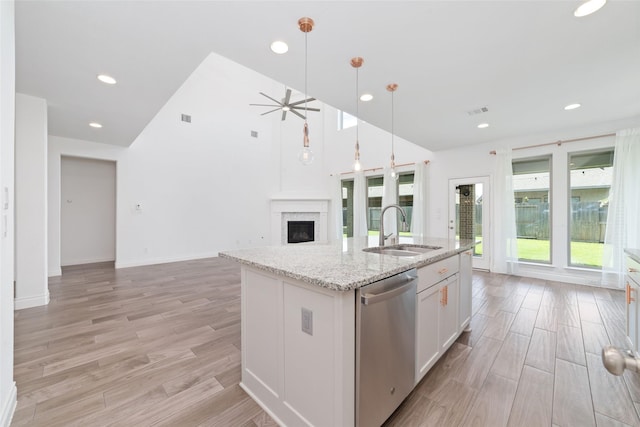 13731 Pedernales Ct, Cypress, TX 77429 - kitchen featuring stainless steel dishwasher, open floor plan, light wood-style floors, an island with sink, and a fireplace