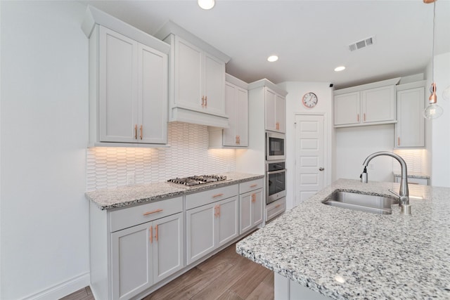 13731 Pedernales Ct, Cypress, TX 77429 - kitchen with stainless steel appliances, light wood-style flooring, tasteful backsplash, light stone counters, and recessed lighting