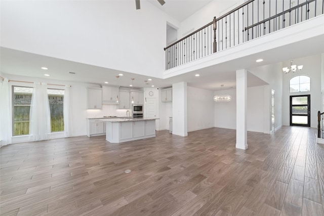 13731 Pedernales Ct, Cypress, TX 77429 - unfurnished living room featuring a chandelier, a high ceiling, light wood-type flooring, and recessed lighting