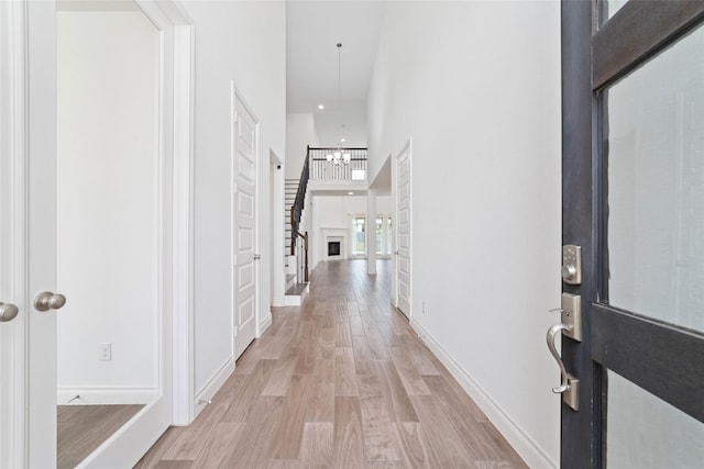 13731 Pedernales Ct, Cypress, TX 77429 - hallway featuring light wood-type flooring, a chandelier, a towering ceiling, and stairway