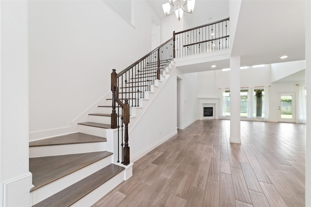 13731 Pedernales Ct, Cypress, TX 77429 - stairs featuring a high ceiling, a glass covered fireplace, wood finished floors, a chandelier, and recessed lighting