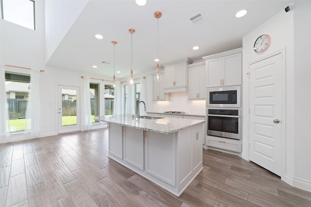 13731 Pedernales Ct, Cypress, TX 77429 - kitchen with stainless steel appliances, an island with sink, healthy amount of natural light, decorative backsplash, and recessed lighting