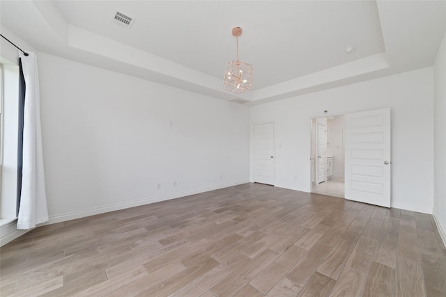 13731 Pedernales Ct, Cypress, TX 77429 - spare room with a tray ceiling, a chandelier, and light wood-type flooring
