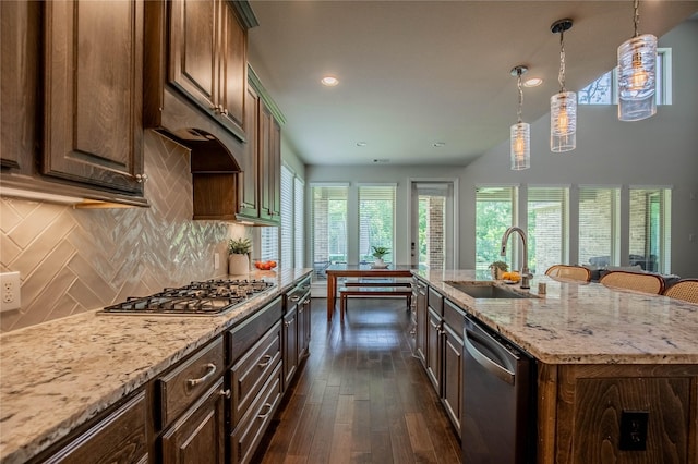 4209 Orchard Pass Dr, Spring, TX 77386 - kitchen featuring appliances with stainless steel finishes, dark wood-type flooring, tasteful backsplash, light stone counters, and a kitchen island with sink
