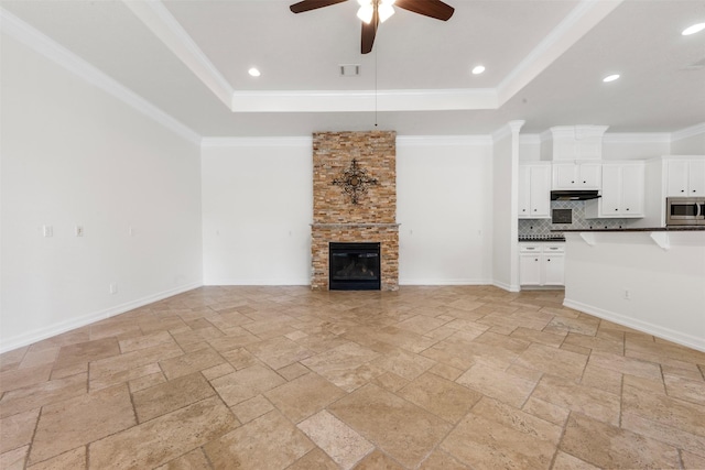 3207 W Benders Landing Blvd, Spring, TX 77386 - unfurnished living room with a tray ceiling, stone tile floors, ceiling fan, a stone fireplace, and ornamental molding