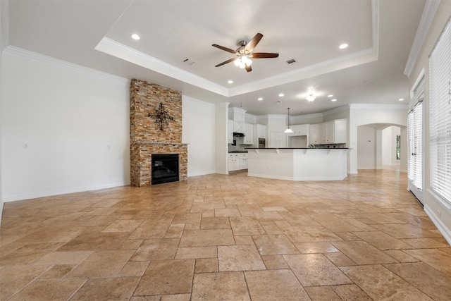 3207 W Benders Landing Blvd, Spring, TX 77386 - unfurnished living room with a raised ceiling, ceiling fan, stone tile floors, arched walkways, and a stone fireplace