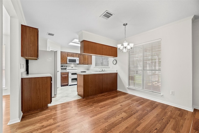 15207 Hillside Park Way, Cypress, TX 77433 - kitchen featuring white appliances, a chandelier, a peninsula, brown cabinetry, and light countertops
