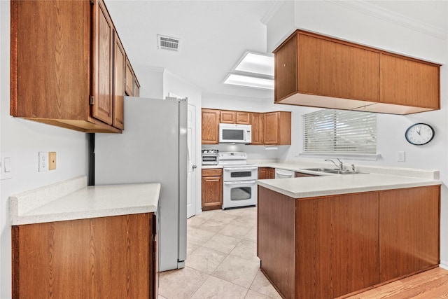 15207 Hillside Park Way, Cypress, TX 77433 - kitchen with white appliances, a peninsula, brown cabinetry, light countertops, and crown molding