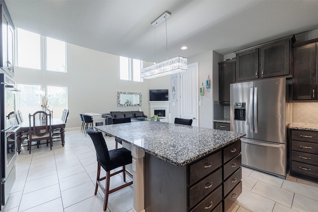 3514 Hampton Landing Ct, Katy, TX 77494 - kitchen featuring stainless steel appliances, a kitchen island, light stone countertops, decorative backsplash, and a kitchen bar