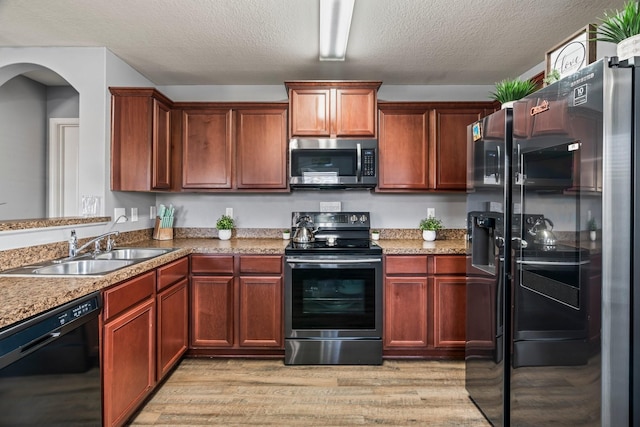12715 Lilac Stone Ct, Houston, TX 77044 - kitchen featuring black appliances, light wood-style floors, a textured ceiling, and arched walkways