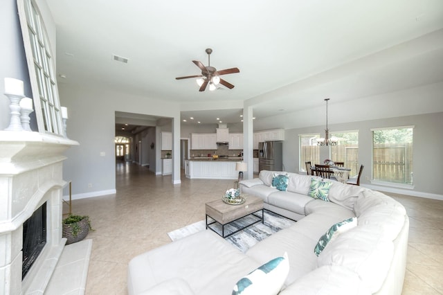 27907 Brandy Creek Ln, Fulshear, TX 77441 - living area with a fireplace with raised hearth, ceiling fan, a chandelier, and light tile patterned floors