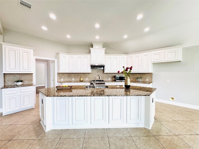27907 Brandy Creek Ln, Fulshear, TX 77441 - kitchen with backsplash, dark stone countertops, white cabinets, a spacious island, and light tile patterned flooring