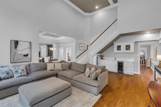 8723 Kennet Valley Rd, Spring, TX 77379 - living area featuring crown molding, bar with sink, wine cooler, light wood finished floors, and stairway
