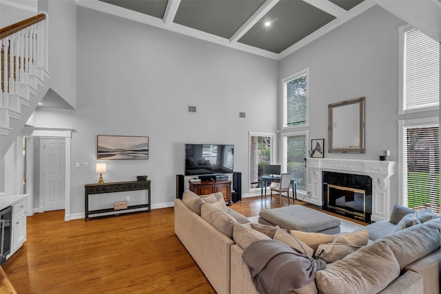8723 Kennet Valley Rd, Spring, TX 77379 - living area featuring a towering ceiling, a high end fireplace, light wood finished floors, crown molding, and stairs