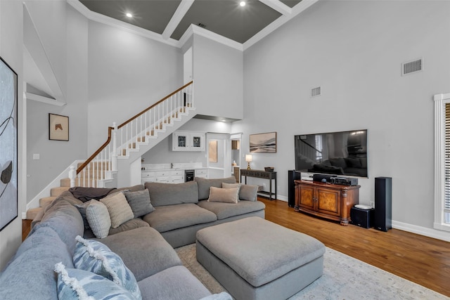 8723 Kennet Valley Rd, Spring, TX 77379 - living room featuring a high ceiling, stairway, wood finished floors, crown molding, and bar area