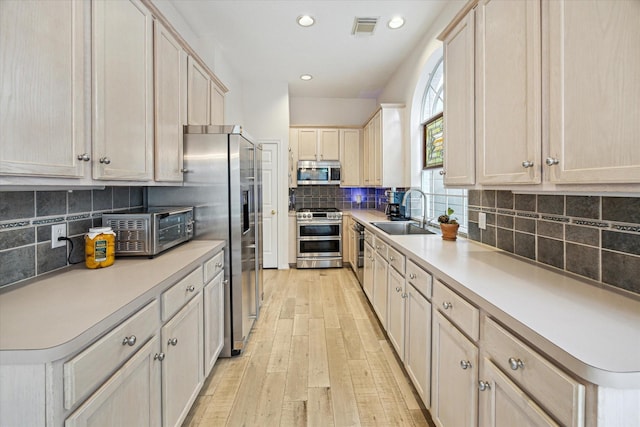 2019 Hazard St, Houston, TX 77019 - kitchen featuring appliances with stainless steel finishes, light wood finished floors, light countertops, tasteful backsplash, and recessed lighting