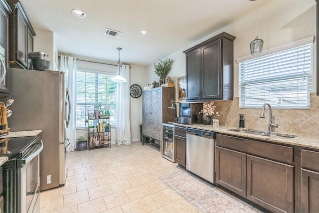 12602 Browning Dr, Montgomery, TX 77356 - kitchen with stainless steel appliances, dark brown cabinetry, backsplash, light stone countertops, and recessed lighting
