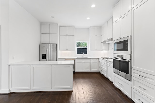 7722 Jacquelyn Oaks Rd, Houston, TX 77055 - kitchen with appliances with stainless steel finishes, backsplash, a peninsula, dark wood-style floors, and recessed lighting