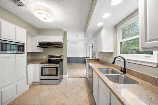 12239 Monticeto Ln, Meadows Place, TX 77477 - kitchen featuring stainless steel appliances, under cabinet range hood, light tile patterned floors, white cabinets, and recessed lighting