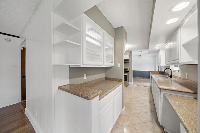 12239 Monticeto Ln, Meadows Place, TX 77477 - kitchen with open shelves, a textured ceiling, white cabinetry, light stone counters, and stainless steel electric range oven