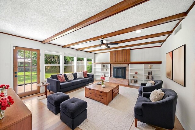 12239 Monticeto Ln, Meadows Place, TX 77477 - living area featuring a textured ceiling, beam ceiling, light wood finished floors, a fireplace, and a ceiling fan
