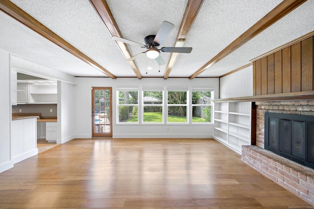12239 Monticeto Ln, Meadows Place, TX 77477 - unfurnished living room with beam ceiling, a textured ceiling, plenty of natural light, a brick fireplace, and a ceiling fan
