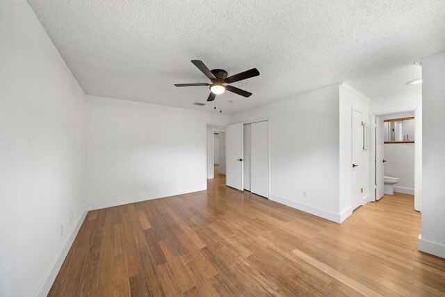 12239 Monticeto Ln, Meadows Place, TX 77477 - unfurnished bedroom featuring light wood finished floors, a ceiling fan, a textured ceiling, a closet, and connected bathroom
