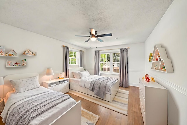 12239 Monticeto Ln, Meadows Place, TX 77477 - bedroom featuring a textured ceiling, light wood-type flooring, and a ceiling fan