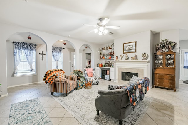18115 Stone Angel Dr, Humble, TX 77346 - living area featuring light tile patterned flooring, ceiling fan, arched walkways, and a tile fireplace