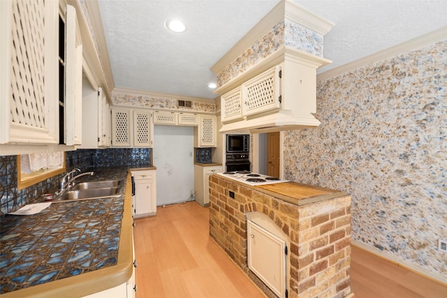 12223 Gladewick Dr, Houston, TX 77077 - kitchen featuring black oven, light wood-style flooring, ornamental molding, a textured ceiling, and built in microwave