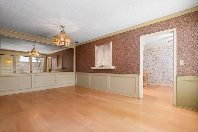 12223 Gladewick Dr, Houston, TX 77077 - unfurnished dining area with a chandelier, wood finished floors, wainscoting, wallpapered walls, and a textured ceiling