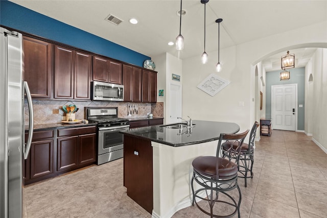 20206 Fossil Valley Ln, Cypress, TX 77433 - kitchen featuring appliances with stainless steel finishes, arched walkways, tasteful backsplash, a breakfast bar, and light tile patterned flooring