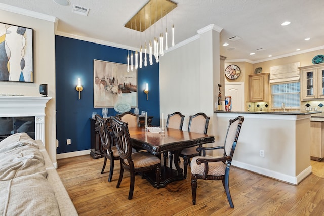 5706 Blossom St, Houston, TX 77007 - dining room with light wood finished floors, ornamental molding, recessed lighting, and a fireplace