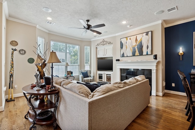 5706 Blossom St, Houston, TX 77007 - living room featuring light wood-style floors, ceiling fan, a textured ceiling, a glass covered fireplace, and recessed lighting