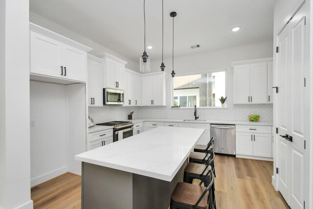 4802 Elysian St Unit C, Houston, TX 77009 - kitchen with appliances with stainless steel finishes, a kitchen breakfast bar, hanging light fixtures, white cabinets, and decorative backsplash