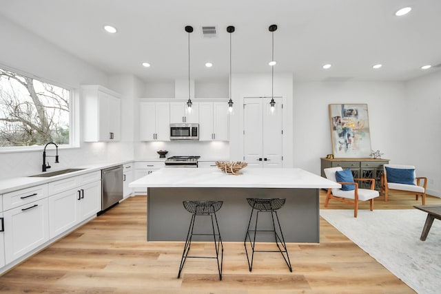 1218 English St, Houston, TX 77009 - kitchen with appliances with stainless steel finishes, a center island, a kitchen bar, white cabinetry, and decorative backsplash
