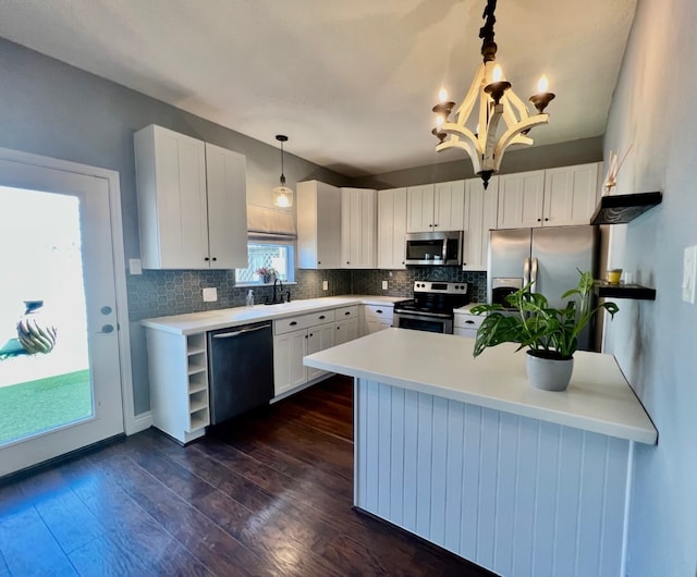 1023 Fountain View Dr, Houston, TX 77057 - kitchen featuring appliances with stainless steel finishes, a peninsula, backsplash, white cabinets, and light countertops