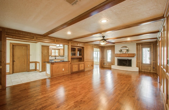 3623 Beech Hill Dr, Spring, TX 77388 - unfurnished living room with a textured ceiling, a brick fireplace, light wood-style flooring, ceiling fan, and beamed ceiling