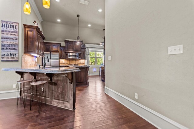 1207 Marigold Ln, Longview, TX 75604 - kitchen featuring stainless steel appliances, dark brown cabinetry, a peninsula, a kitchen breakfast bar, and tasteful backsplash