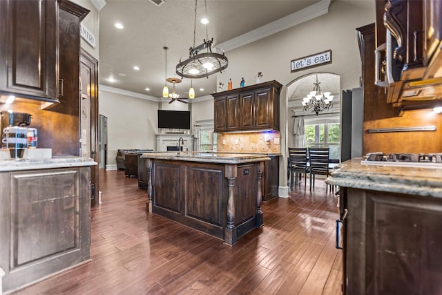 1207 Marigold Ln, Longview, TX 75604 - kitchen with a chandelier, open floor plan, a kitchen island, crown molding, and dark brown cabinetry
