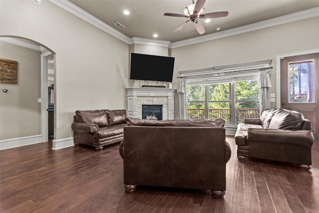 1207 Marigold Ln, Longview, TX 75604 - living area featuring a stone fireplace, ceiling fan, dark wood finished floors, ornamental molding, and arched walkways