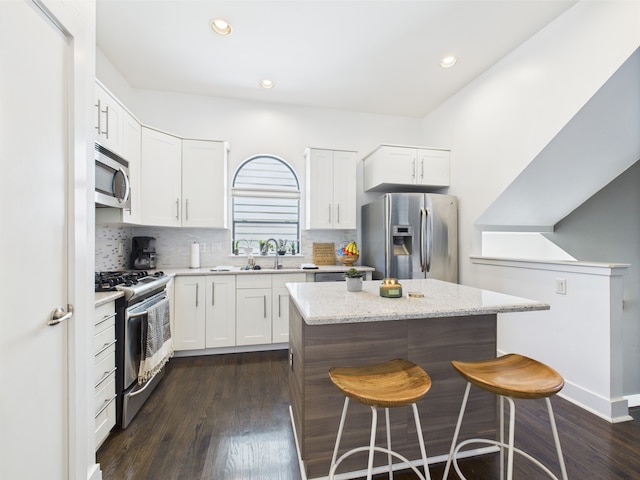 5810 Darling St Unit F, Houston, TX 77007 - kitchen featuring appliances with stainless steel finishes, a center island, a kitchen breakfast bar, decorative backsplash, and dark wood-style flooring